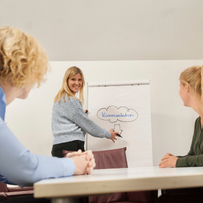 Trainerin der Agentur für Freundlichkeit an Flipchart, die kundenorientiertes Verhalten im Training verbessert