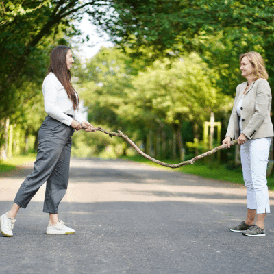 foerderung-der-resilienz_resilienz-training_frauen-halten-stock Förderung der Resilienz, Resilienz trainieren, Zwei Frauen stehen sich gegenüber und halten an beiden Enden einen Stock fest