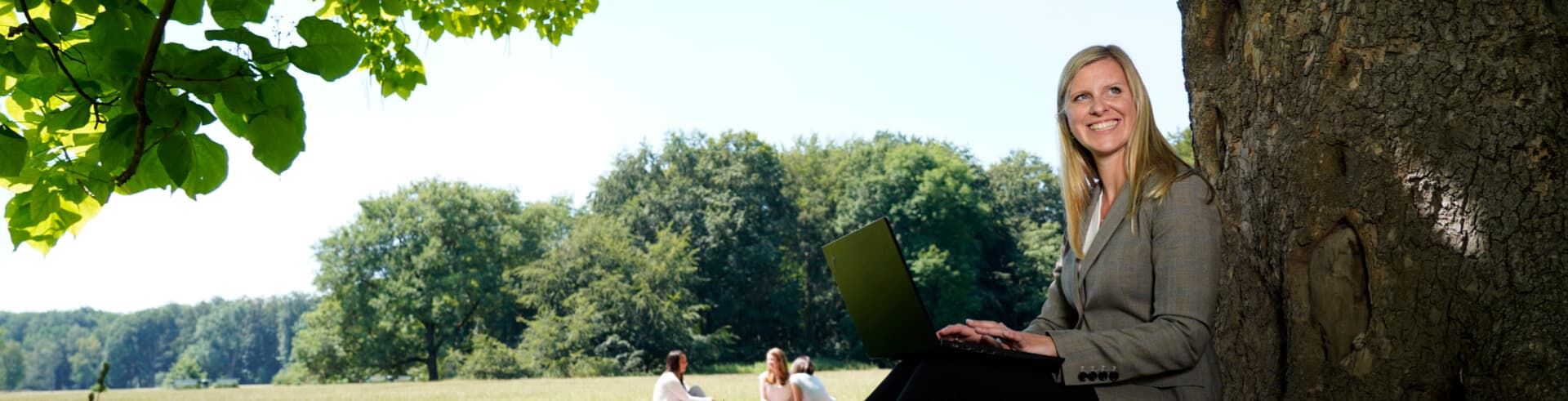 Online-Coaching, Online-Coaching Unternehmen, Frau mit Laptop vor Baum sitzend